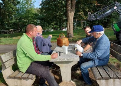 4 Männer auf einer Bank trinken Kaffee